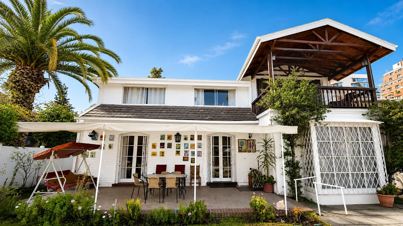 Frente de Casa Menar: terraza con toldo, palmera, balcón de madera y rejas blancas en las ventanas