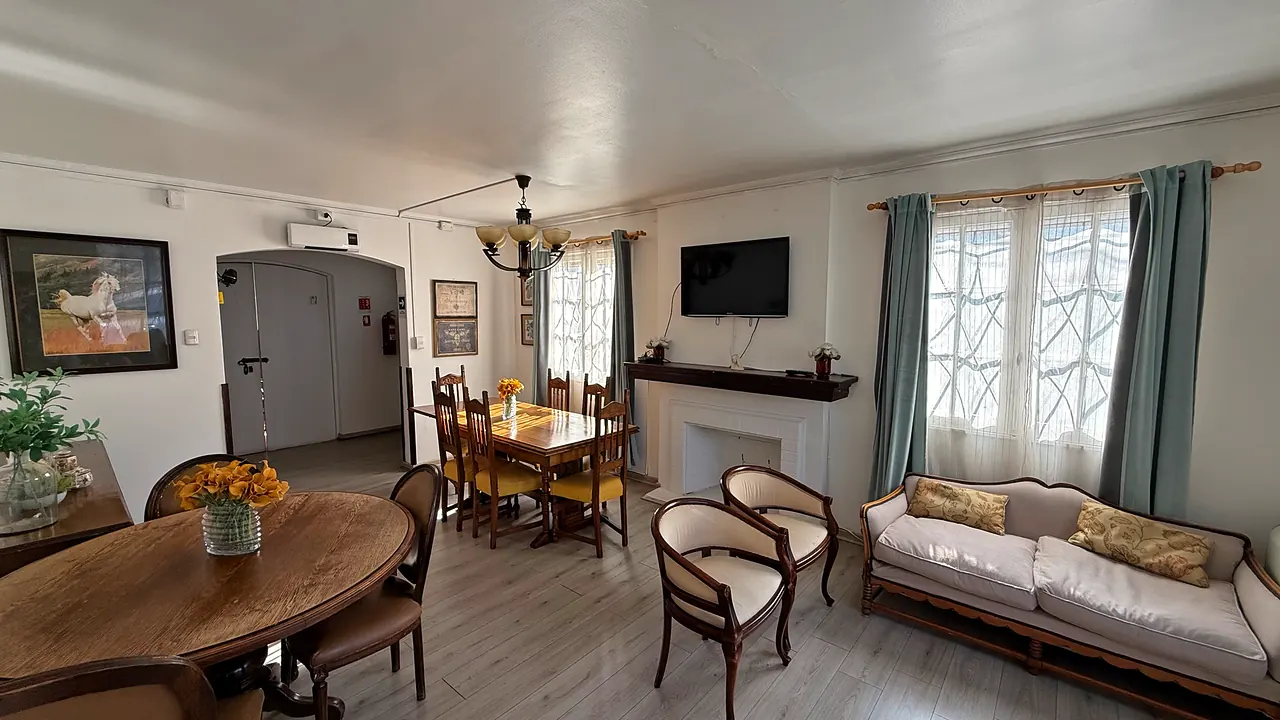 Living de Casa Menar, con sofá, sillones, chimenea y una mesa ovalada de madera
